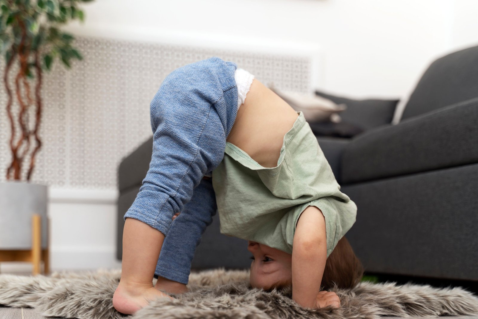 Little boy bending over in front of couch touching his toys.