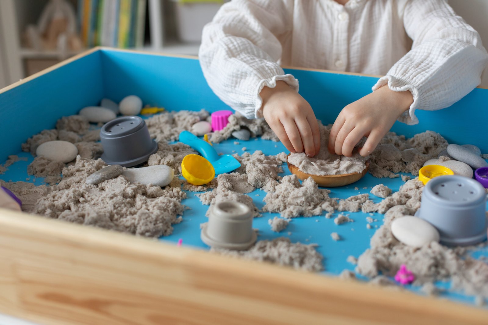 Children activity with kinetic sand for motor and sensory development. Toddler play therapy with colorful toys on sandbox.