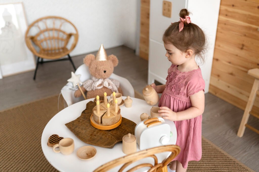 A young girl engaged in a pretend tea party with a teddy bear, using wooden play food and tea set, fostering imagination and social skills.