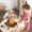 A young girl engaged in a pretend tea party with a teddy bear, using wooden play food and tea set, fostering imagination and social skills.