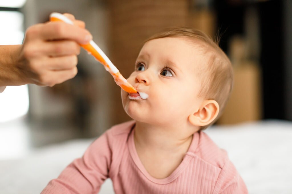 Young baby being fed pureed baby food on a spoon
