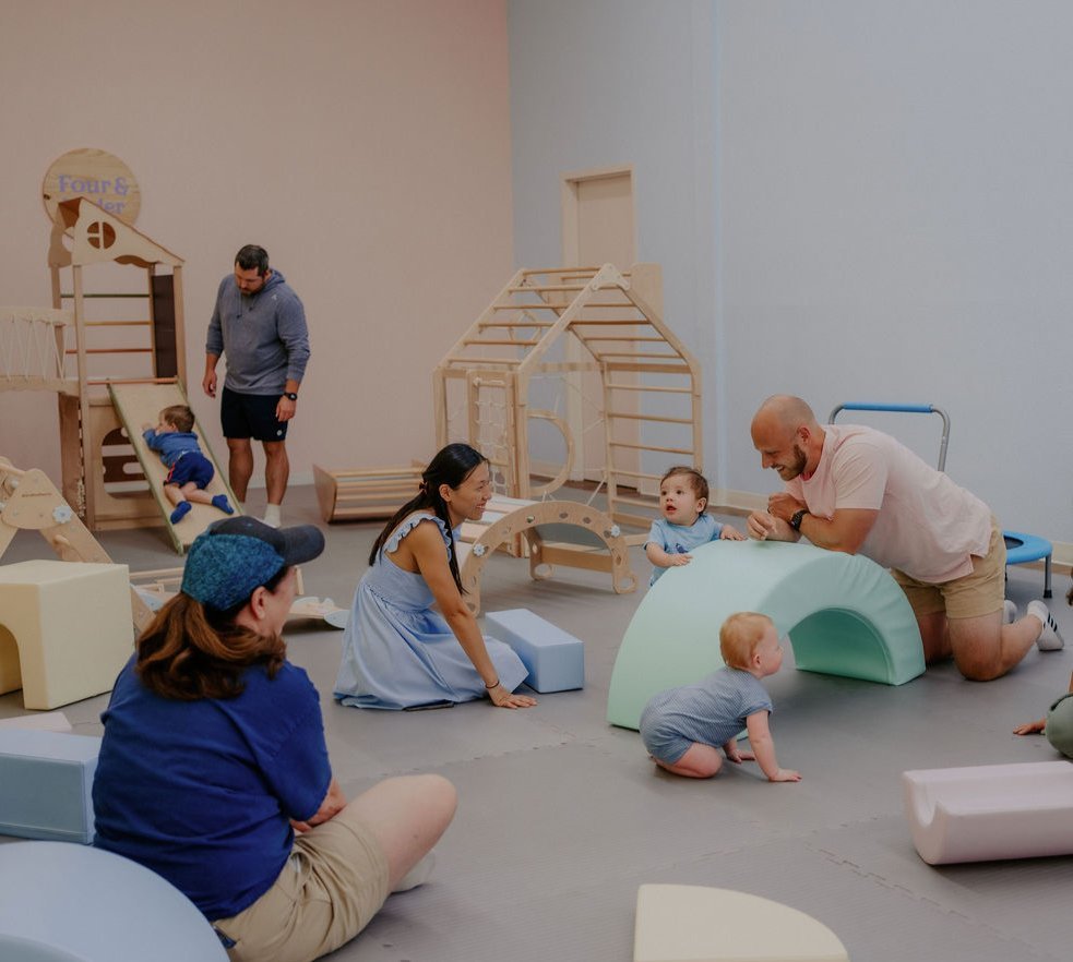 Parents playing with babies and toddlers in the Baby University climbing area
