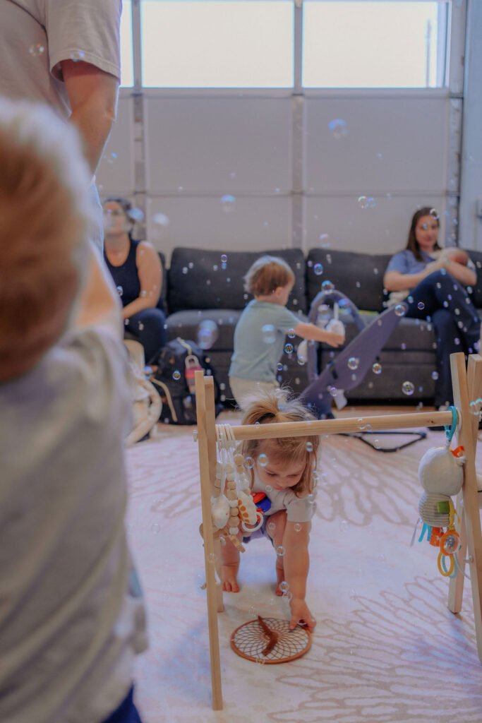 Baby playing at an activity gym in the Baby University lounge while parents relax on the couches