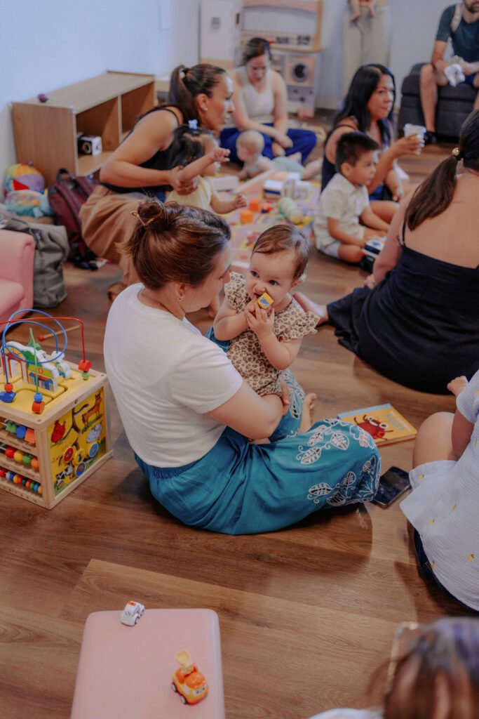 Moms sitting on the floor with their babies in the Baby University parent lounge