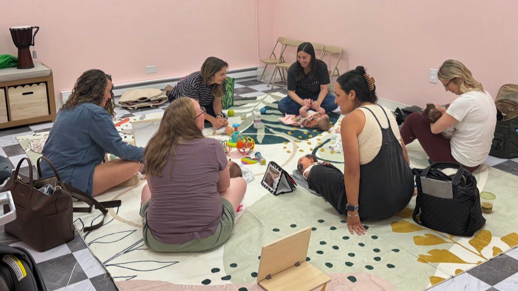 Moms chatting in a circle with their babies at a Mom Village meetup at Baby University