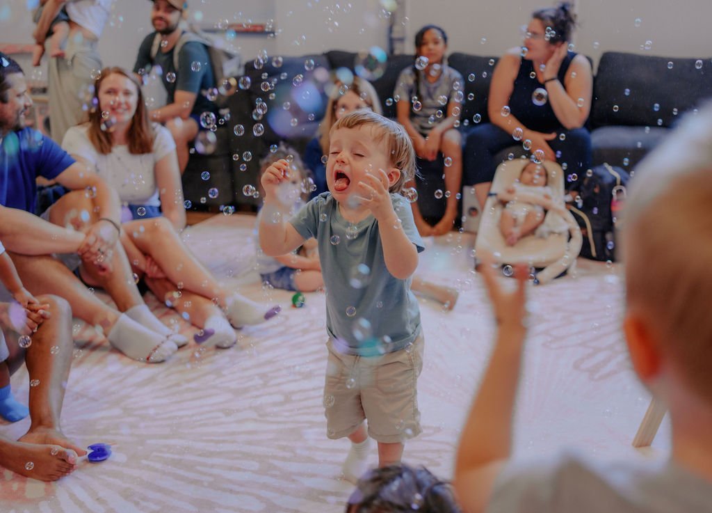 A toddler laughing and catching bubbles at Baby University